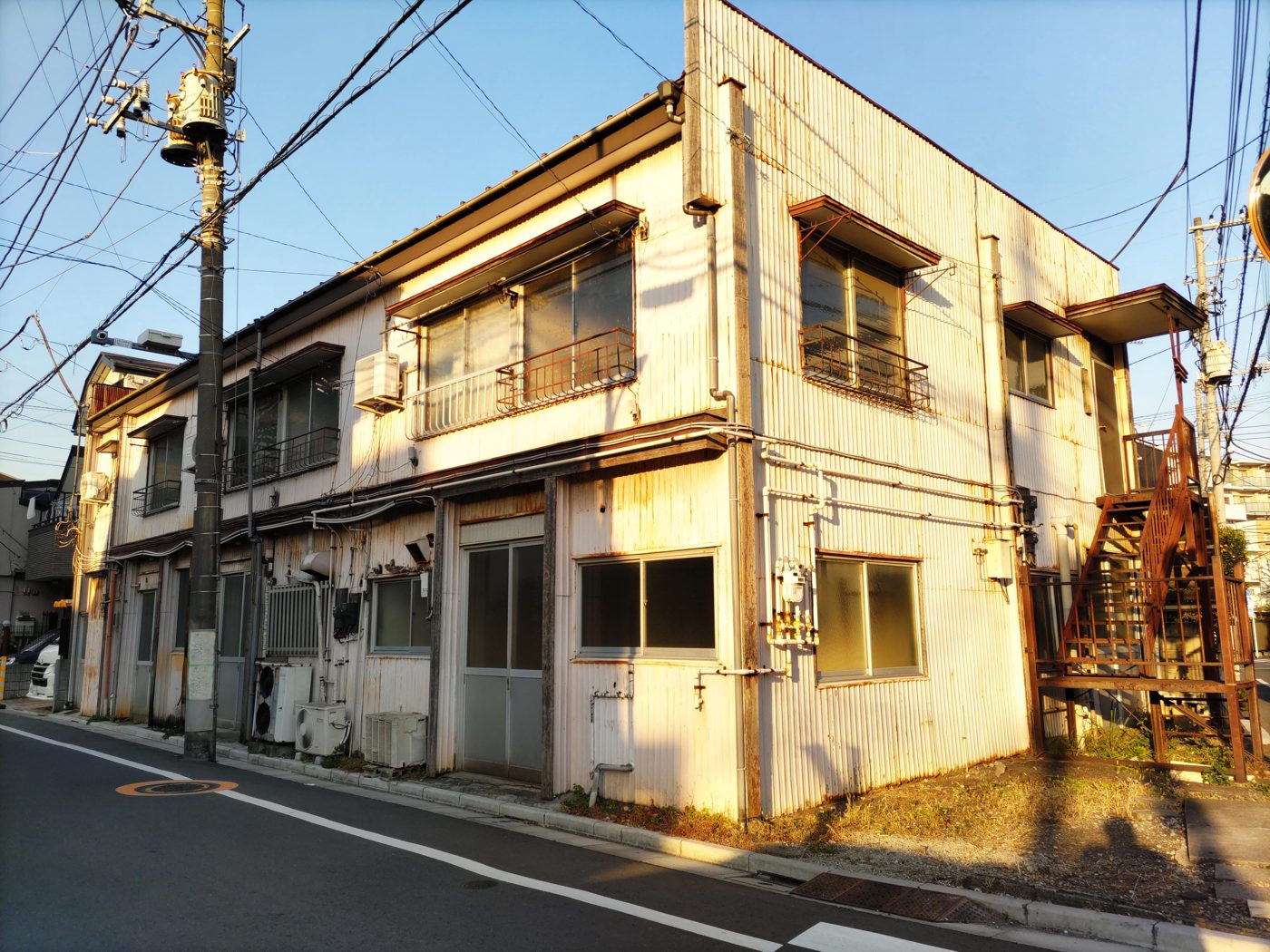 夕日を受けるモルタル外壁の古い2階建てアパート
