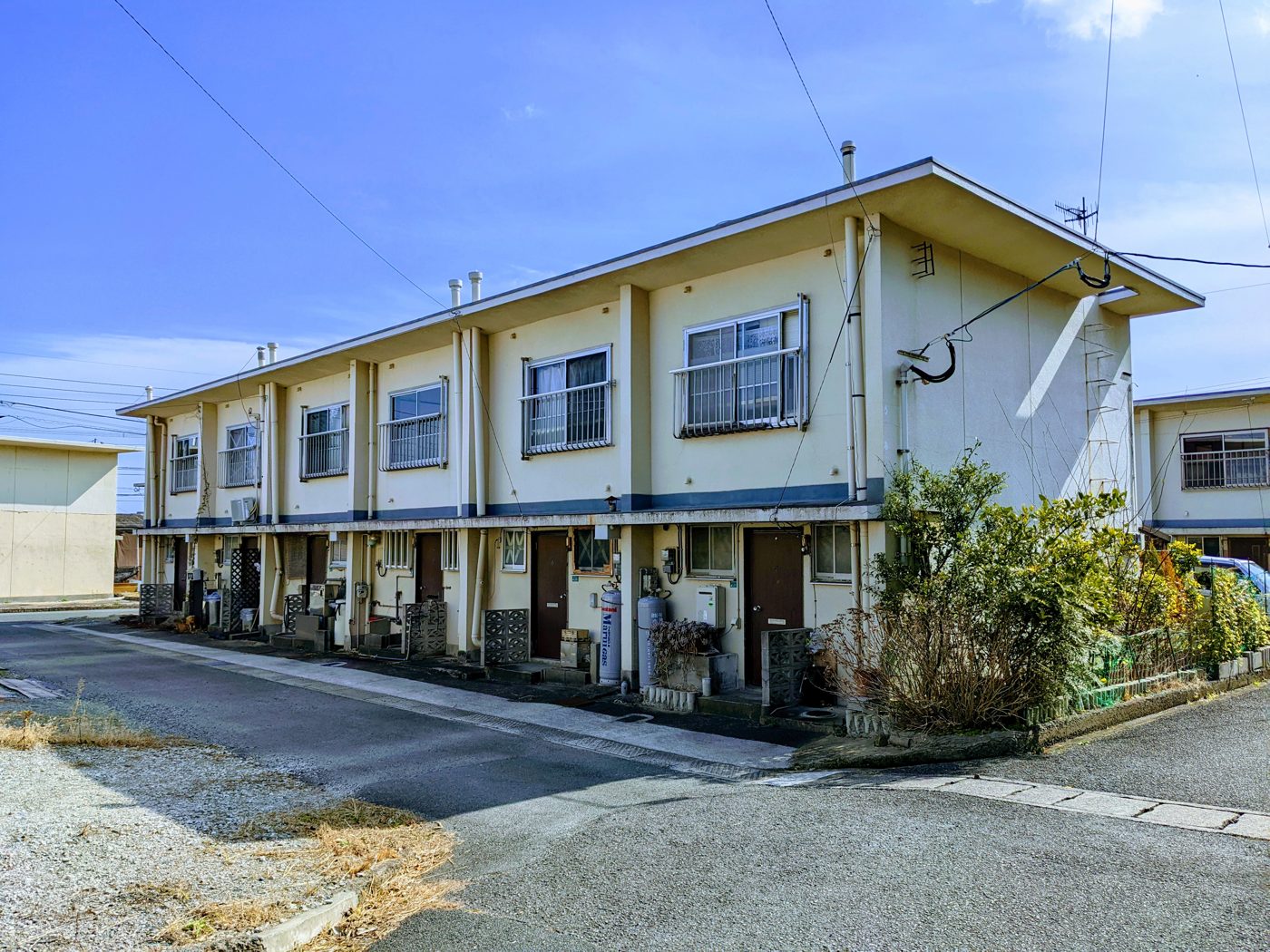2階建ての古い連棟式アパートと前面道路