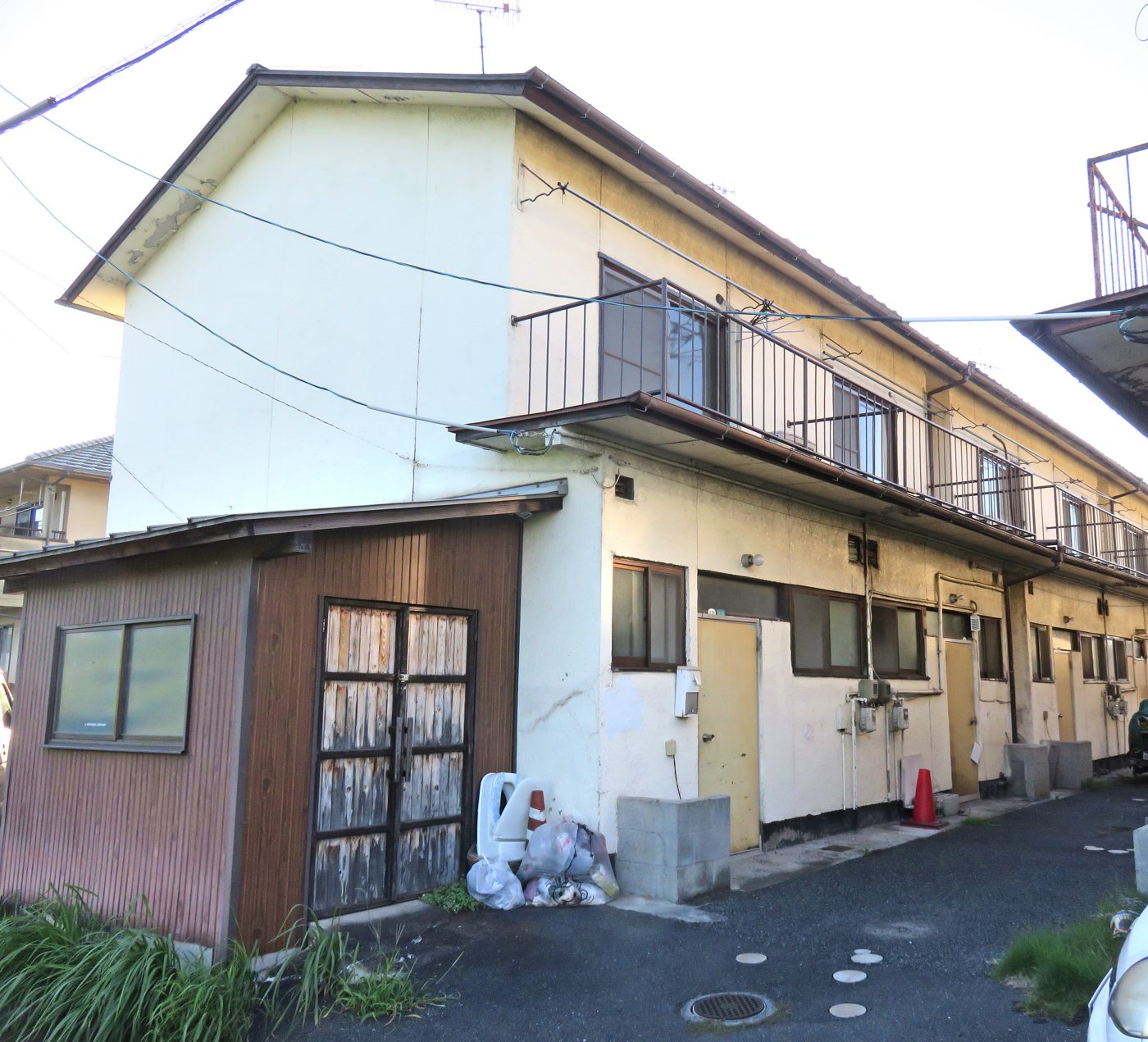 物置が並ぶ古い2階建てアパートの前面